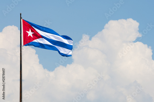 Fotografie Cuban flag flying from a flagpole in the wind in front of a soft blue sky with t