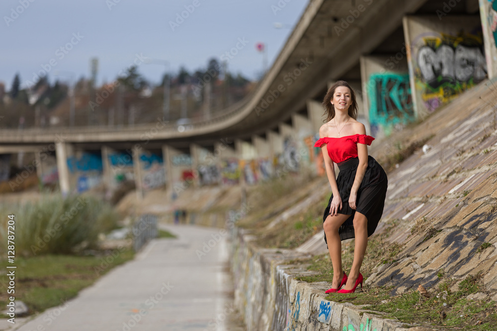 Stylish young woman standing at a highway bridge