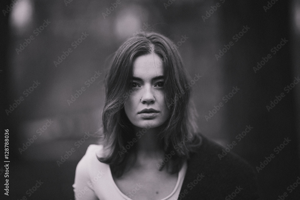 Attractive, charming young woman in a white cotton dress and dark coat walking in the autumn Park. Cloudy. Soft colors of nature. The melancholy mood. Black and white photo.