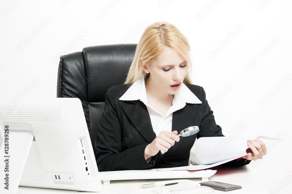 Businesswoman looking through a magnifying glass to documents Businesswoman looking through a magnifying glass to documents