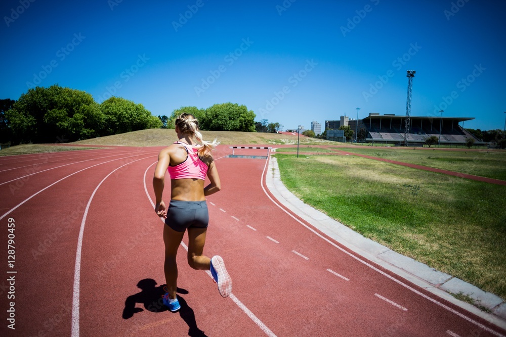 Rear view of female athlete running on the racing track