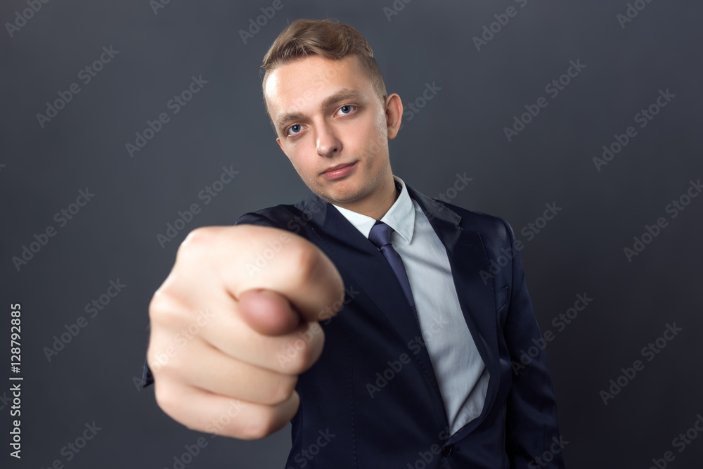 Handsome businessman standing on gray background and and showing fig gesture Handsome businessman standing on gray background and and showing fig gesture