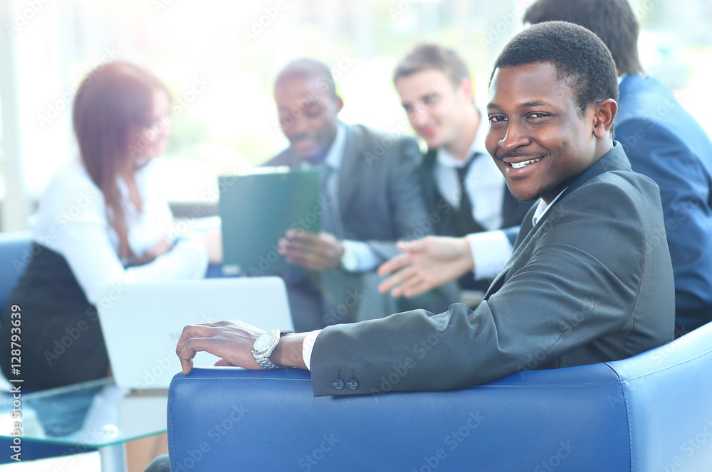 Portrait of smiling African American business man with executives working in background Portrait of smiling African American business man with executives working in background