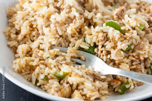 A serving of dirty rice, a traditional cajun and creaole dish, in a white bowl with a fork