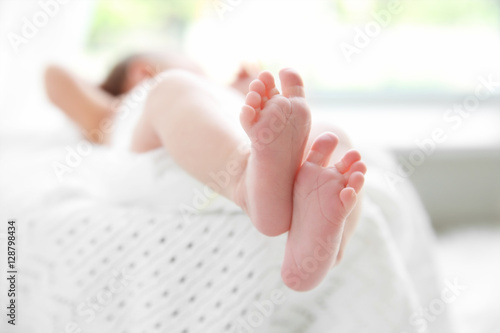 Feet of newborn baby girl lying on soft blanket