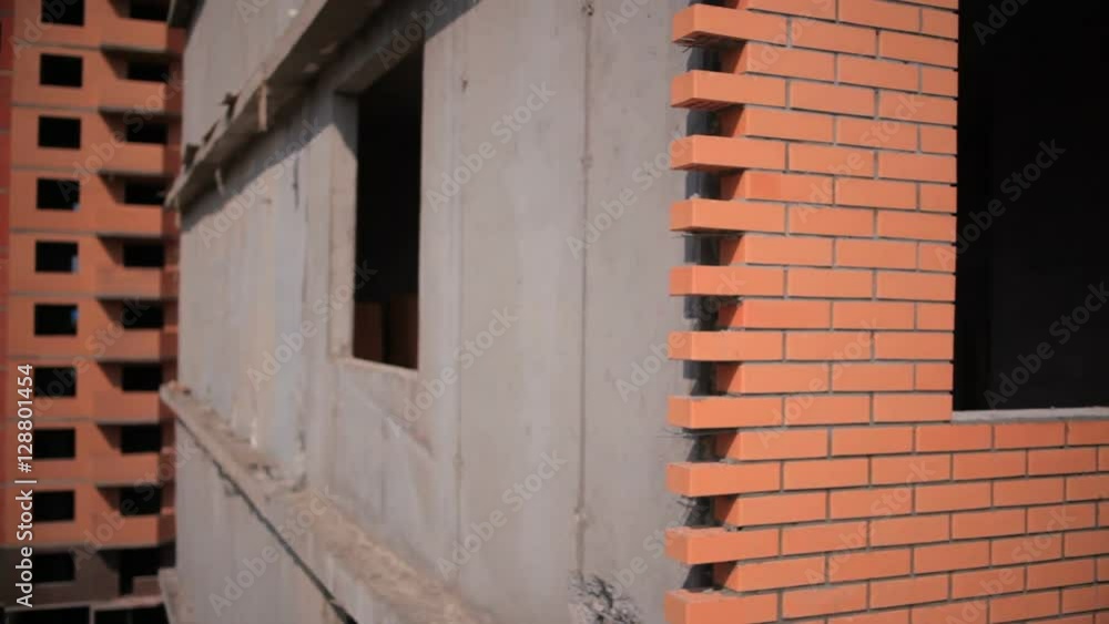 The construction of plants and factories . The camera goes up along the wall of a brick house. In the background an unfinished house The construction of plants and factories . The camera goes up along the wall of a brick house. In the background an unfinished house