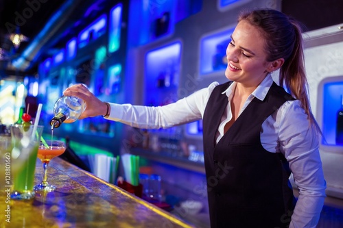 Beautiful bartender pouring drink in glass