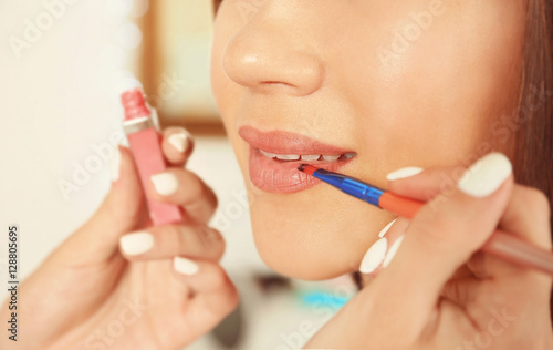 Professional makeup artist applying lip gloss