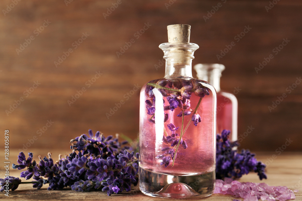 Bottle with aroma oil, sea salt and lavender flowers on wooden background Bottle with aroma oil, sea salt and lavender flowers on wooden background