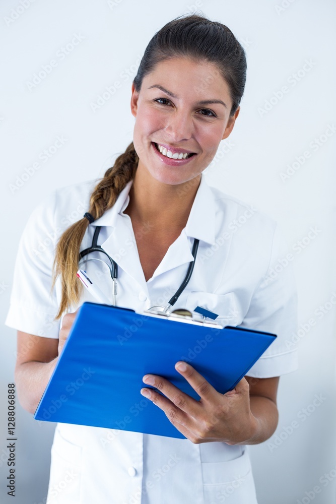 Portrait of female doctor writing on clipboard in hospital Portrait of female doctor writing on clipboard in hospital