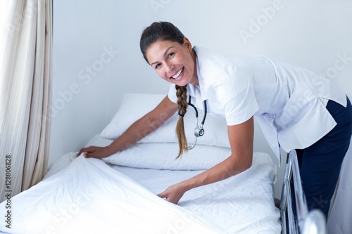 Fotografi Portrait of smiling female doctor preparing the bed