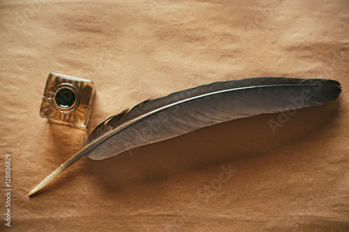 Feather pen and inkwell on paper background