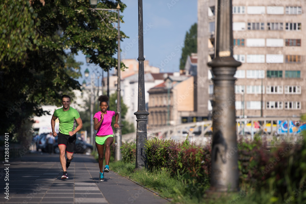 young smiling multiethnic couple jogging in the city