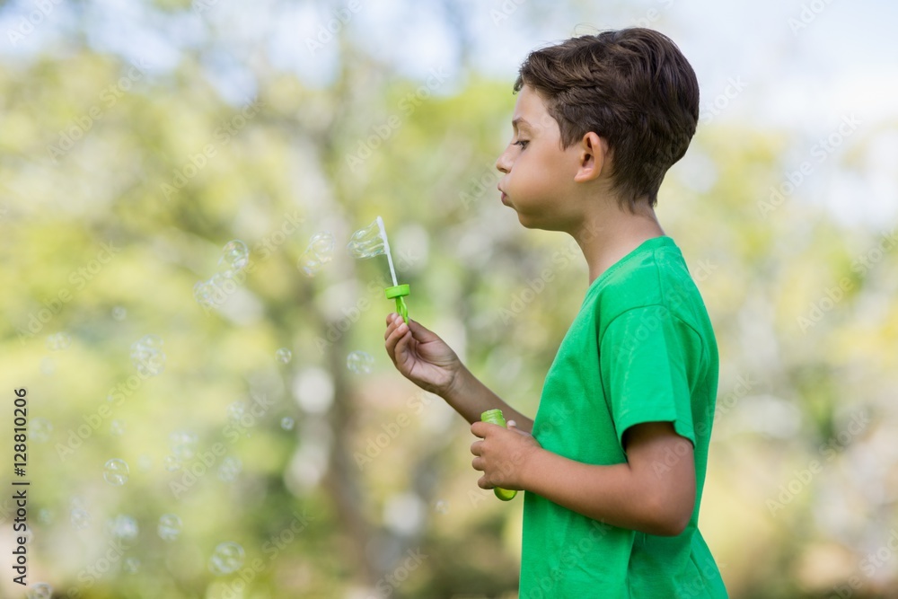 Young boy blowing bubbles through bubble wand Young boy blowing bubbles through bubble wand