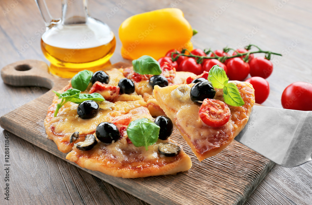 Sliced tasty pizza and fresh cherry tomatoes on wooden cutting board Sliced tasty pizza and fresh cherry tomatoes on wooden cutting board