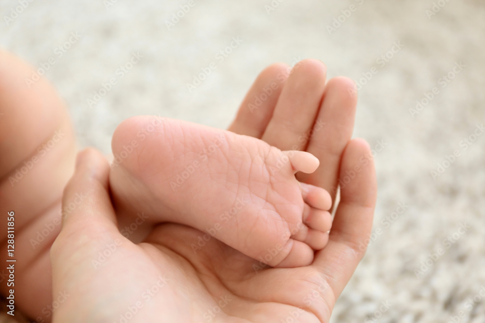 Woman holding cute small baby foot, closeup Woman holding cute small baby foot, closeup