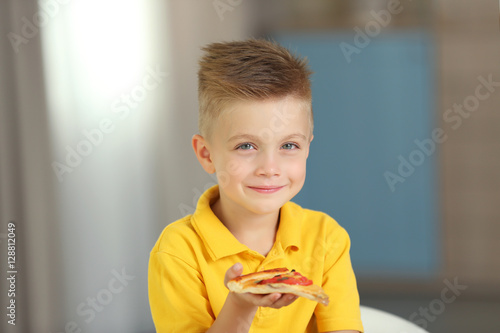 Cute boy eating pizza at home