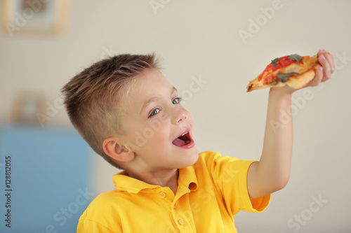Cute boy eating pizza at home