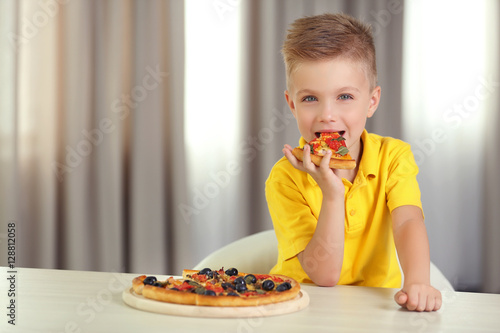 Cute boy eating pizza at home