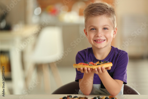 Cute boy eating pizza at home