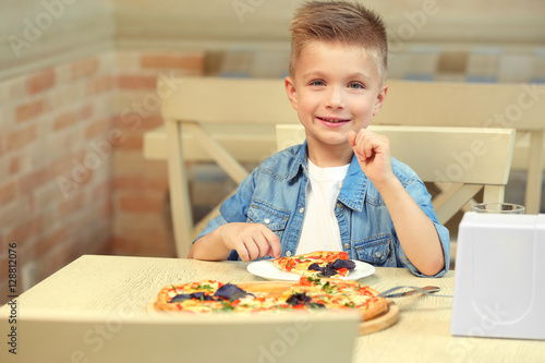 Cute boy eating pizza in restaurant