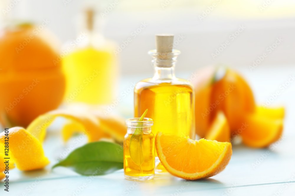 Two bottles with essential oil, orange slice, peel and leaf on wooden table Two bottles with essential oil, orange slice, peel and leaf on wooden table