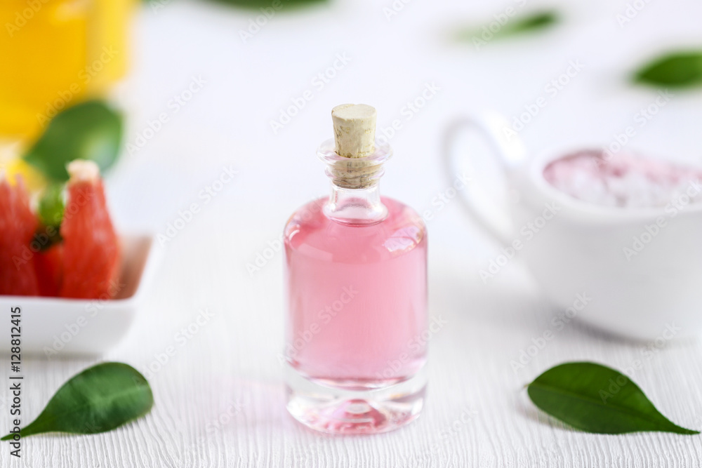 Bottle with essential oil and leaves on wooden table Bottle with essential oil and leaves on wooden table