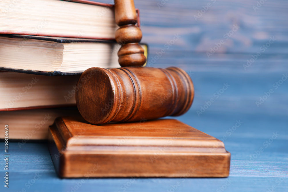 Judge's gavel and books on wooden wall background Judge's gavel and books on wooden wall background