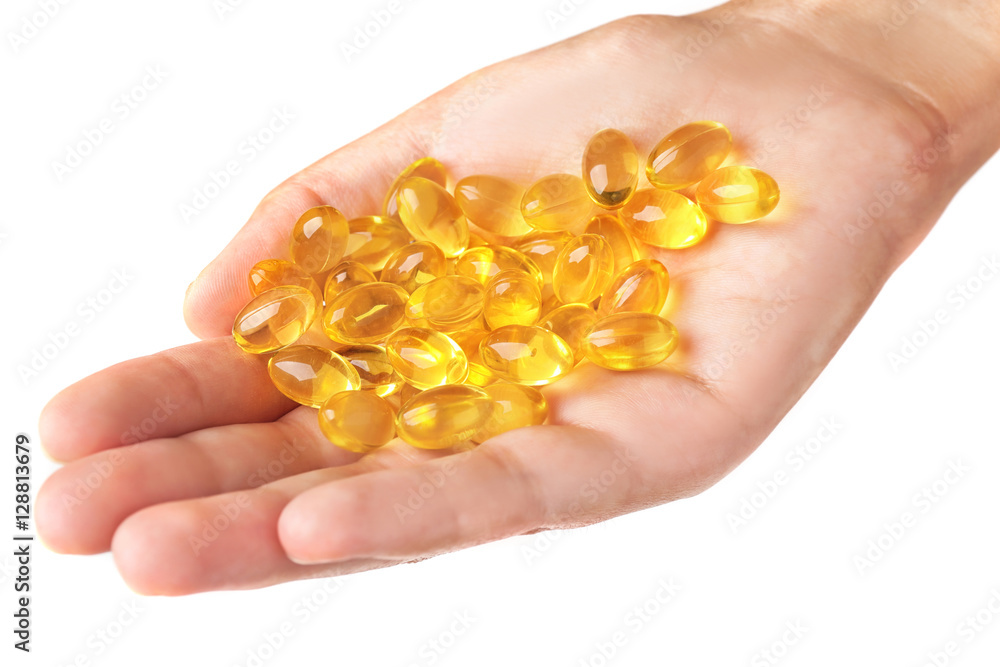 Fish oil pills in female hand on light background