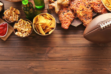 Tasty snacks and rugby ball on wooden table