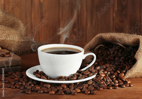 Cup of fresh coffee and sack with beans, closeup