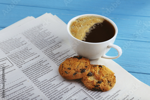 Fresh tasty coffee and newspaper on blue background