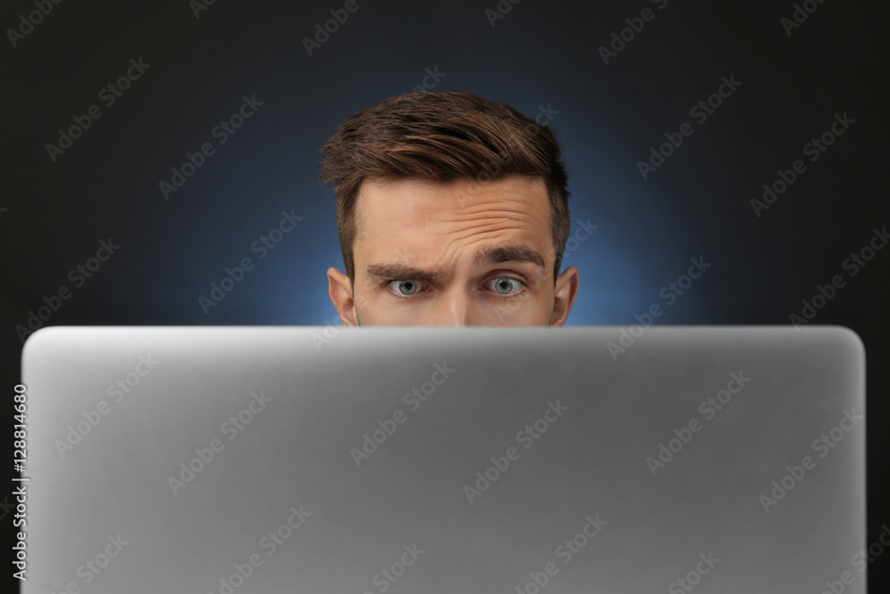 Man sitting at computer monitor on dark background Man sitting at computer monitor on dark background