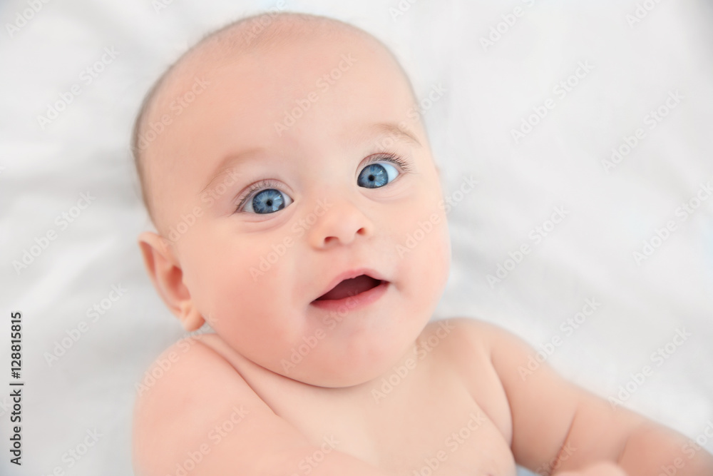 Cute baby lying on white bed sheet, close up view Cute baby lying on white bed sheet, close up view