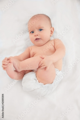 Cute baby lying on white bed sheet
