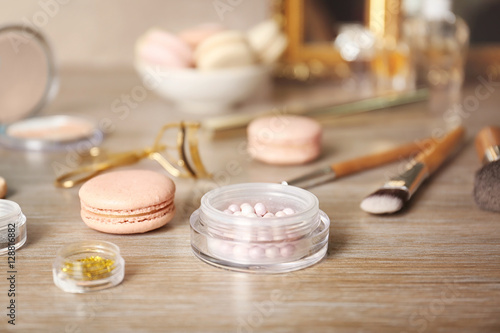 Tasty macaroons and beauty accessories on table