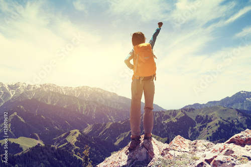  cheering young woman hiker at mountain top