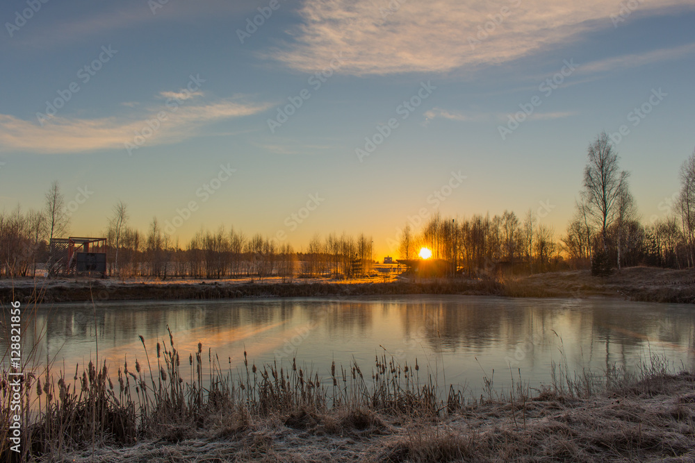 Dramatic winter landscape with frozen lake and sunrise.