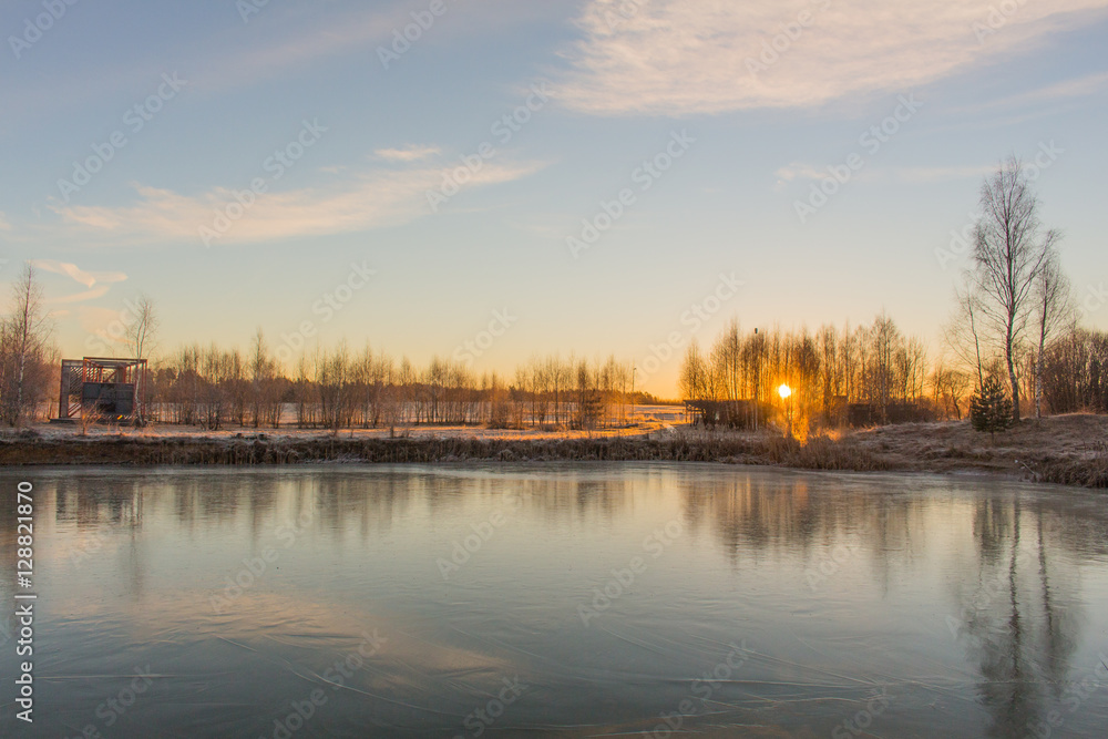 Winter landscape with frozen lake and sunset sky.