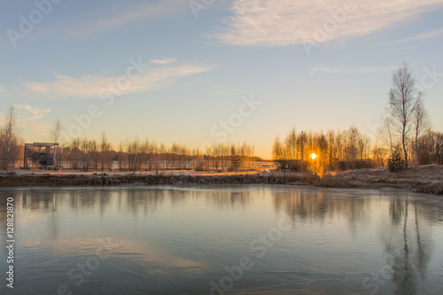 Winter landscape with frozen lake and sunset sky.