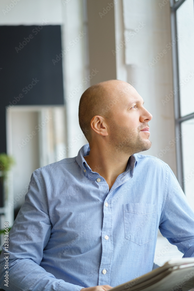 mann hält eine zeitung in der hand und blickt aus dem fenster mann hält eine zeitung in der hand und blickt aus dem fenster