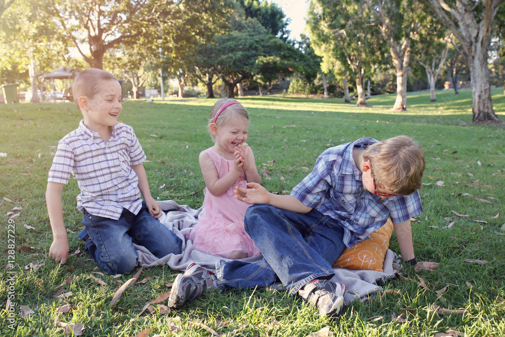 Fototapeta premium Happy brothers and sister playing at the park
