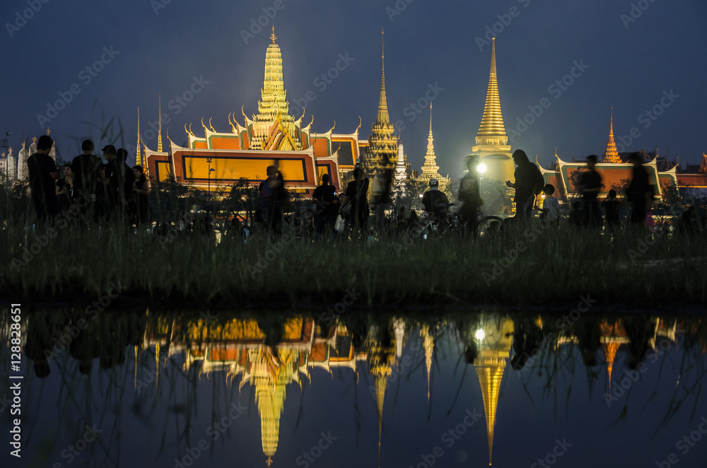 Naklejka premium BANGKOK, THAILAND - OCT 14, 2016: Wat Phra Kaew was reflected on water with people in black shirt. The royal procession transferring the body of the King, at the Grand Palace, Bangkok.
