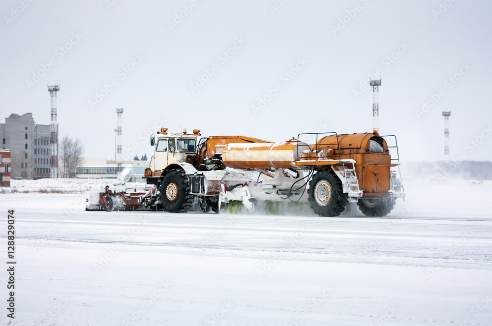 Airfield sweeper cleans the taxiway at the cold winter airport Airfield sweeper cleans the taxiway at the cold winter airport