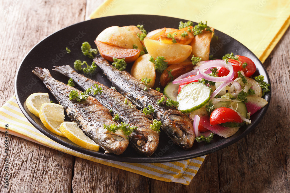 Fried sardines with roasted potatoes and fresh salad closeup. horizontal Fried sardines with roasted potatoes and fresh salad closeup. horizontal