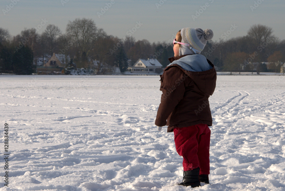 little girl gazing at the sun on frozen lake 