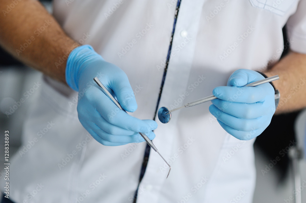 dental instruments in the hands of the doctor. Dentist in sterile latex gloves holding dental tools Close-up dental instruments in the hands of the doctor. Dentist in sterile latex gloves holding dental tools Close-up