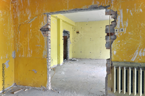 The process of repair, reconstruction of the building. Peeled yellow wall, gray concrete floor and broken doorways.