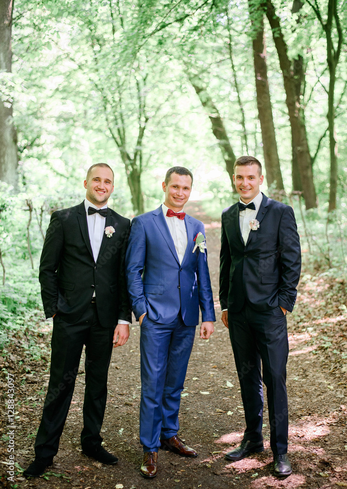 happy and young groom and his friends standing together outdoors happy and young groom and his friends standing together outdoors