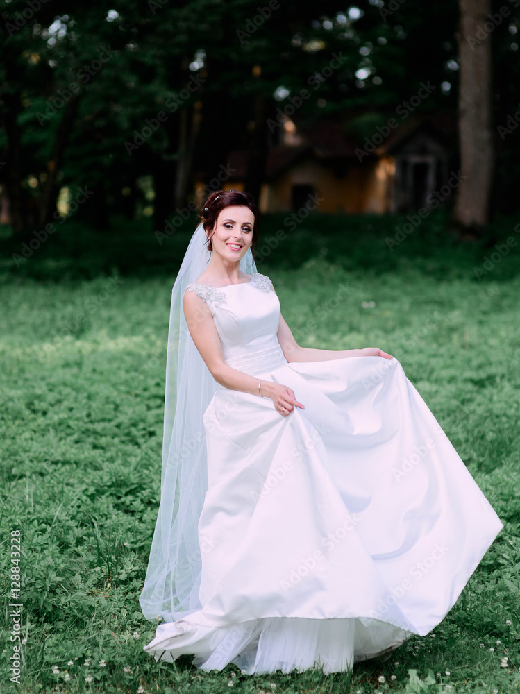 happy and beautiful bride in white dress standing outdoors